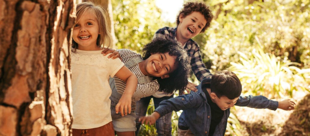 children playing hide and seek behind a tree